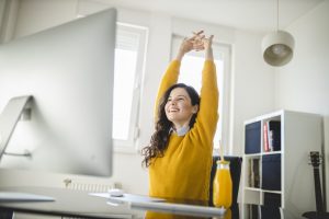 mujer haciendo estiramientos delante del ordenador